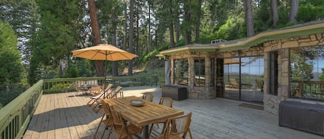 A wooden deck with a table and chairs, surrounded by trees.