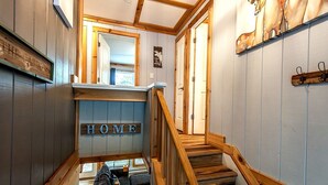 A wooden staircase with a 'HOME' sign at the top, leading to a living area with a sofa and a small table. - Charming 3-bedroom condo with Pool, Hot Tub, AC  & Games (Beech Mountain)