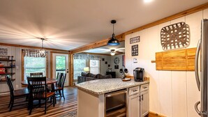 A kitchen with a central island, wooden flooring, and a coffee bar sign. - Charming 3-bedroom condo with Pool, Hot Tub, AC  & Games (Beech Mountain)