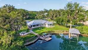 A house with a dock and boats, surrounded by greenery and trees.