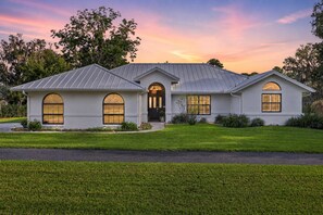 A two-story house with a metal roof, large windows, and a well-maintained lawn.