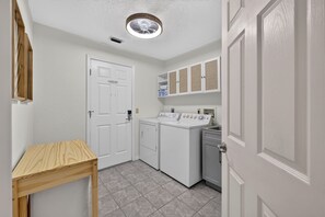 A laundry room with a washing machine, dryer, and a small table.