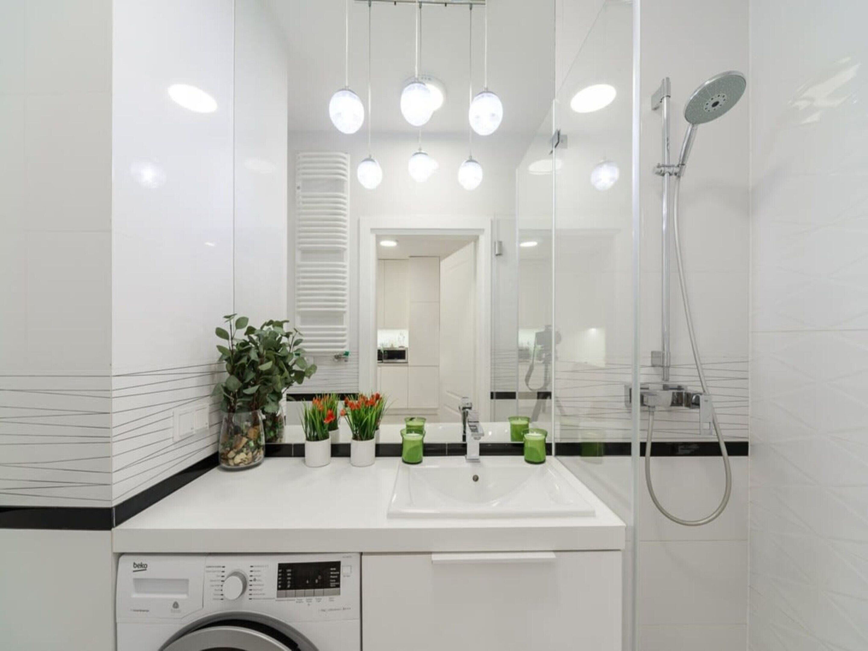 Uma casa de banho moderna com uma sanita branca, espelho e chuveiro.