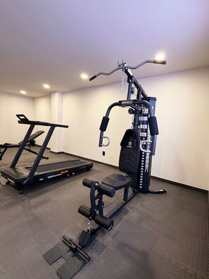 Et fitnessrum med løbebånd, vægtbænk og forskellig træningsudstyr.
