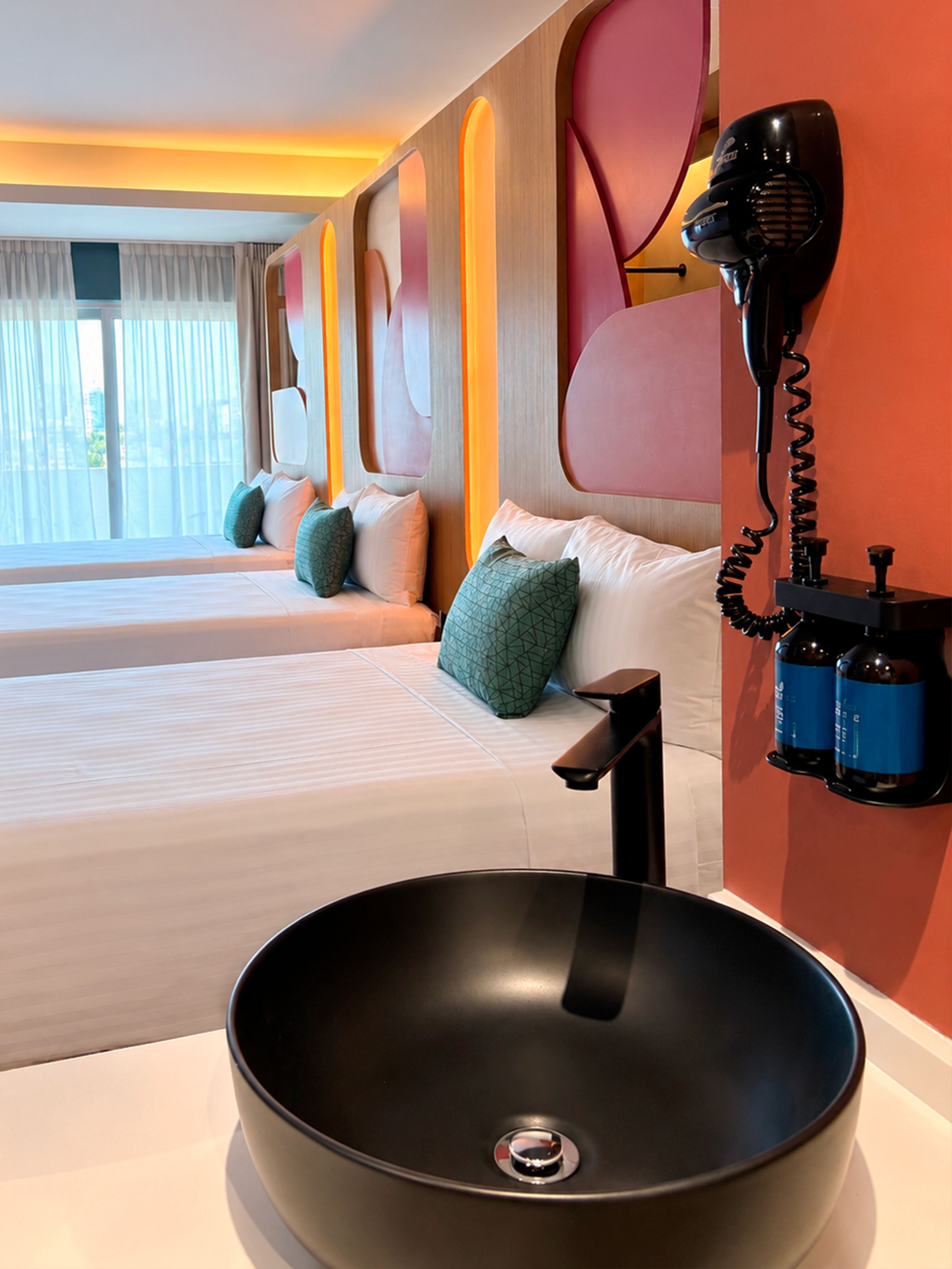 Habitación de hotel con una cama grande, una mesita de noche, un lavamanos negro y un secador de pelo montado en la pared.