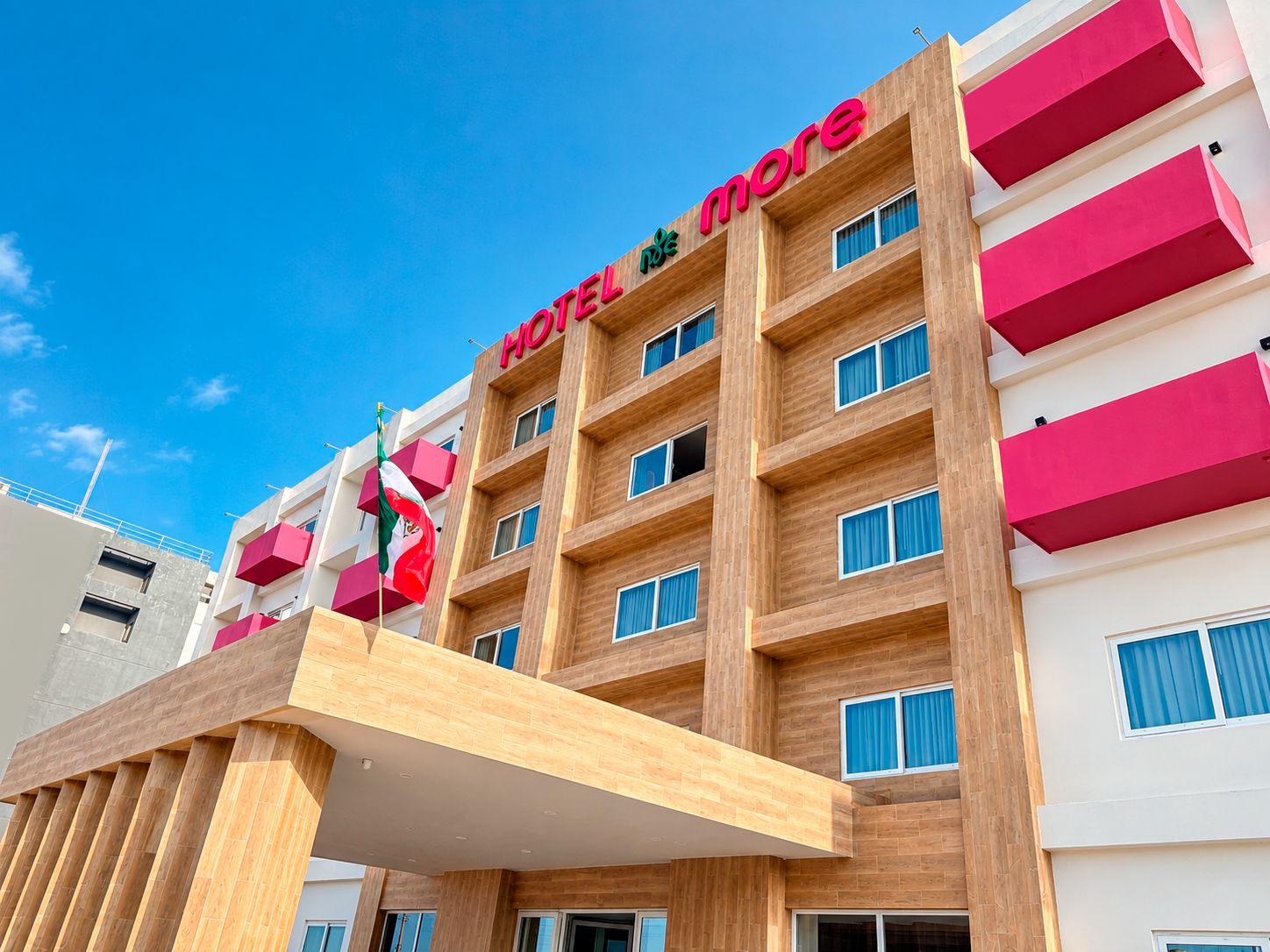 Un edificio de hotel con fachada moderna, varios balcones y cielo despejado.