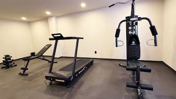Ett gym med löpband, bänk och styrketräningsmaskin.