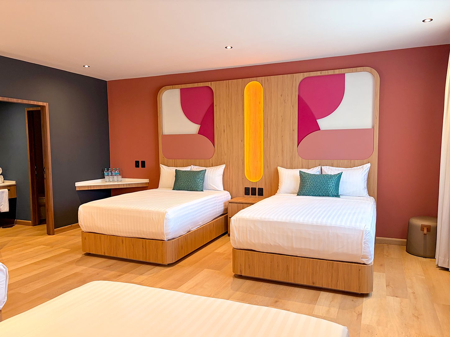 A hotel room with two beds, a small table, and a trash bin.