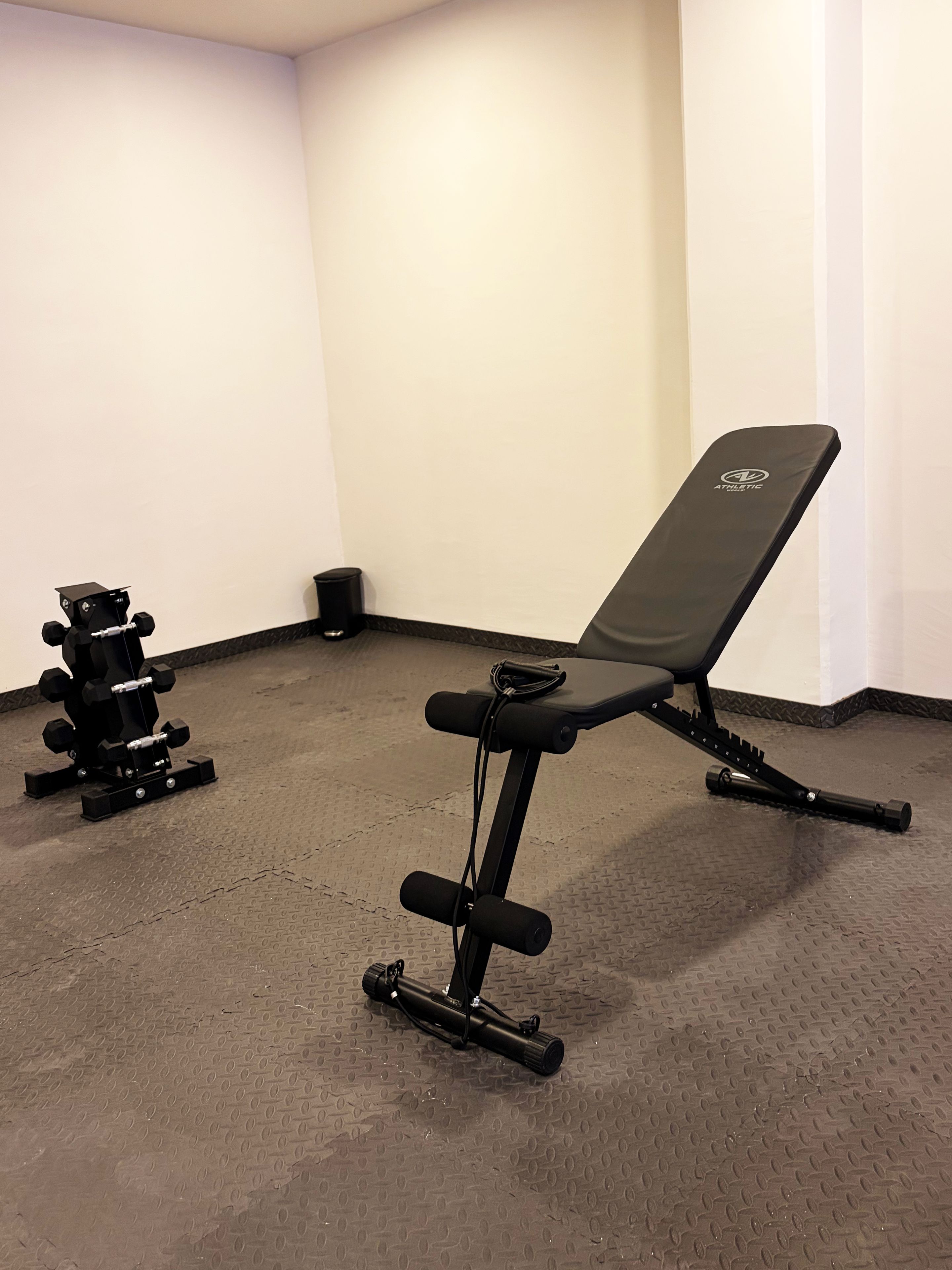 Un gimnasio con banco y máquinas de pesas.