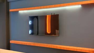 Una habitación de hotel moderna con una cama, un televisor montado en la pared y una estantería de madera.
