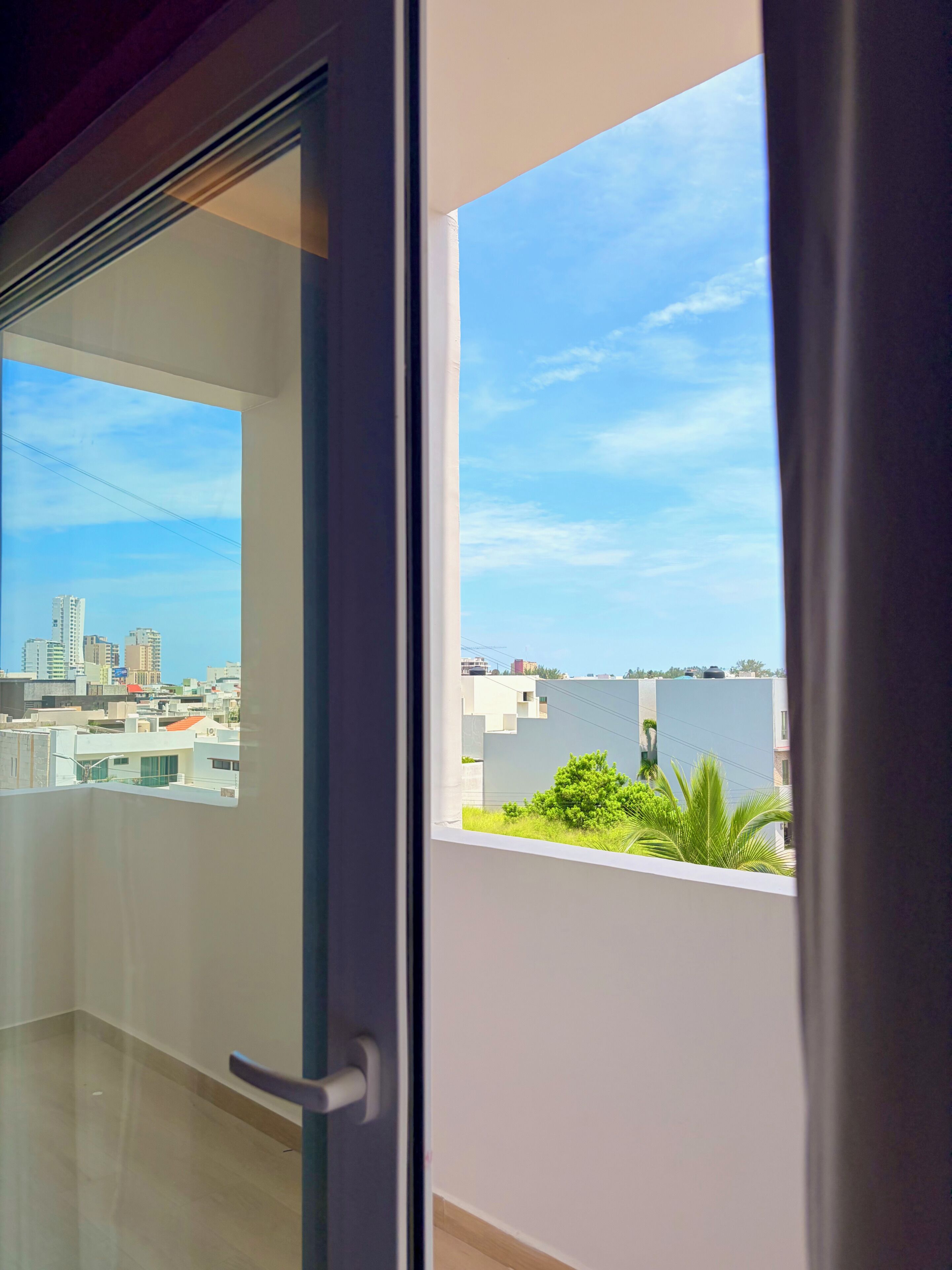 A view from a balcony with a cityscape and a body of water in the distance.