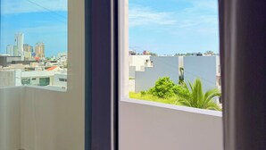 A view from a balcony with a cityscape and a body of water in the distance.