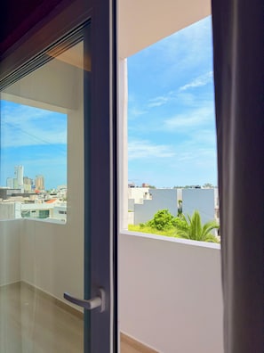 A view from a balcony with a cityscape and a body of water in the distance.