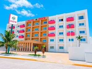Un hotel de varios pisos con un letrero llamativo, balcones y cielo despejado.