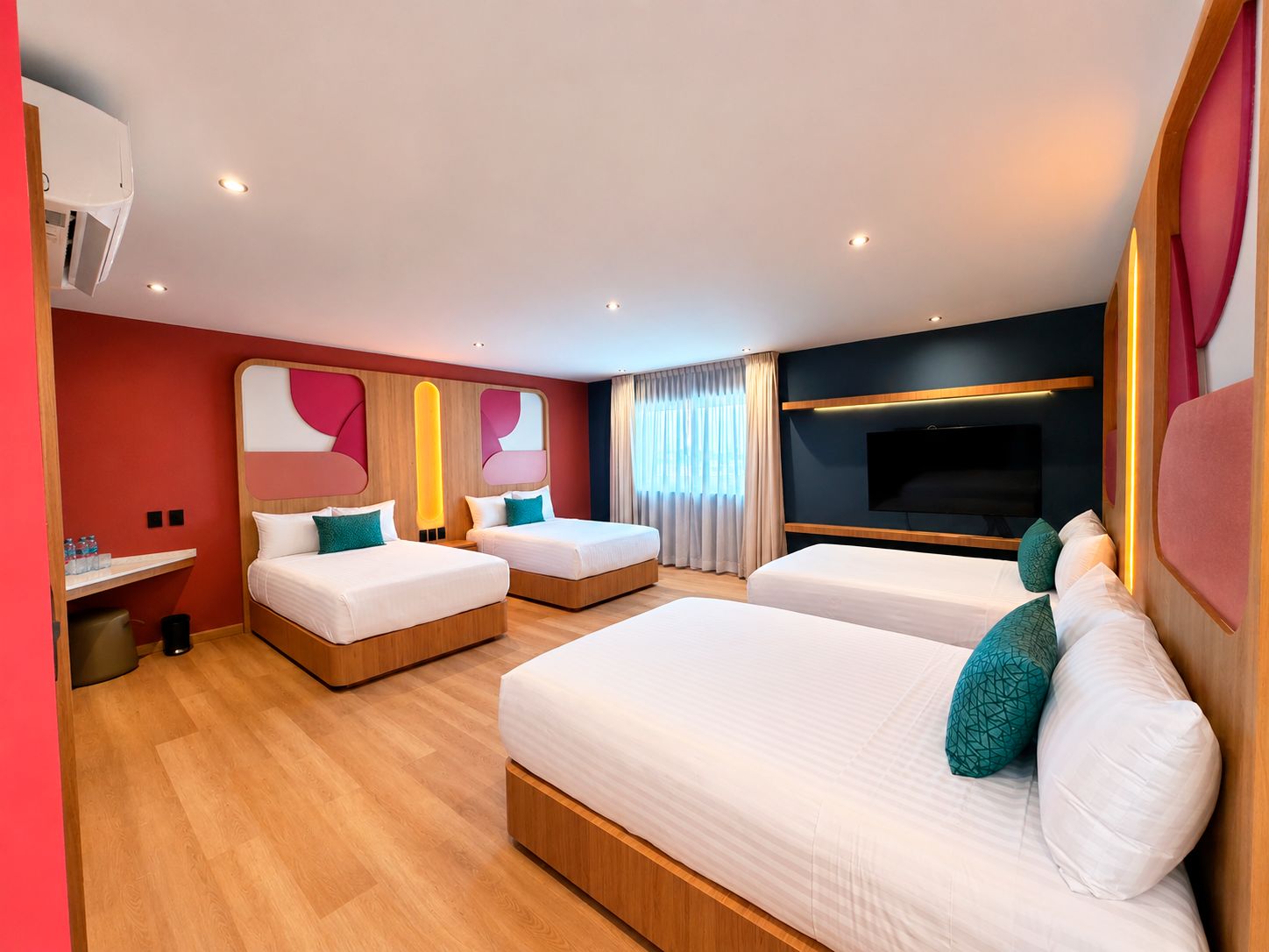 A hotel room with two beds, a TV, and a small seating area.