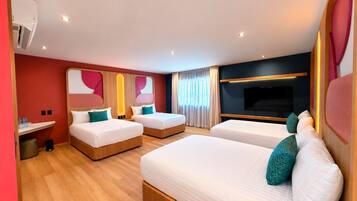 A hotel room with two beds, a TV, and a small seating area.