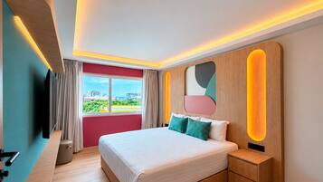 Habitación de hotel moderna con una cama grande, una mesita de noche, televisión y vistas a la ciudad.