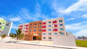 A multi-story hotel with a modern design, featuring balconies and a flat roof.