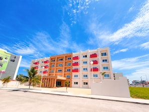 A multi-story hotel with a modern design, featuring balconies and a flat roof.