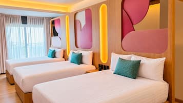 Habitación de hotel con tres camas, un ventanal grande con cortinas y un diseño moderno en la pared con formas geométricas.