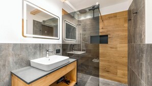 A modern bathroom with a large mirror, two sinks, and a shower area. - Vrbo Property (Marebbe)