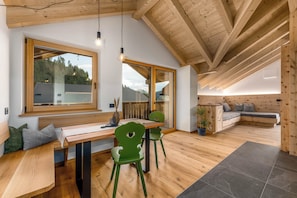A modern interior with a wooden ceiling, a dining area with a table and chairs, and a seating area with a sofa. - Vrbo Property (Marebbe)
