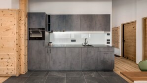 A modern kitchen with grey cabinetry, a stainless steel range hood, and a built-in dishwasher. - Stay calm! Family-Friendly Apartment in Val Badia: Experience the Dolomites (Marebbe)