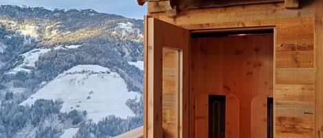 A wooden cabin with a balcony overlooking a snowy mountain landscape.