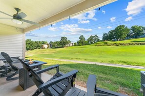 A covered patio with outdoor furniture and a view of a golf course. - The Fairway at the Pointe Royale (Branson)