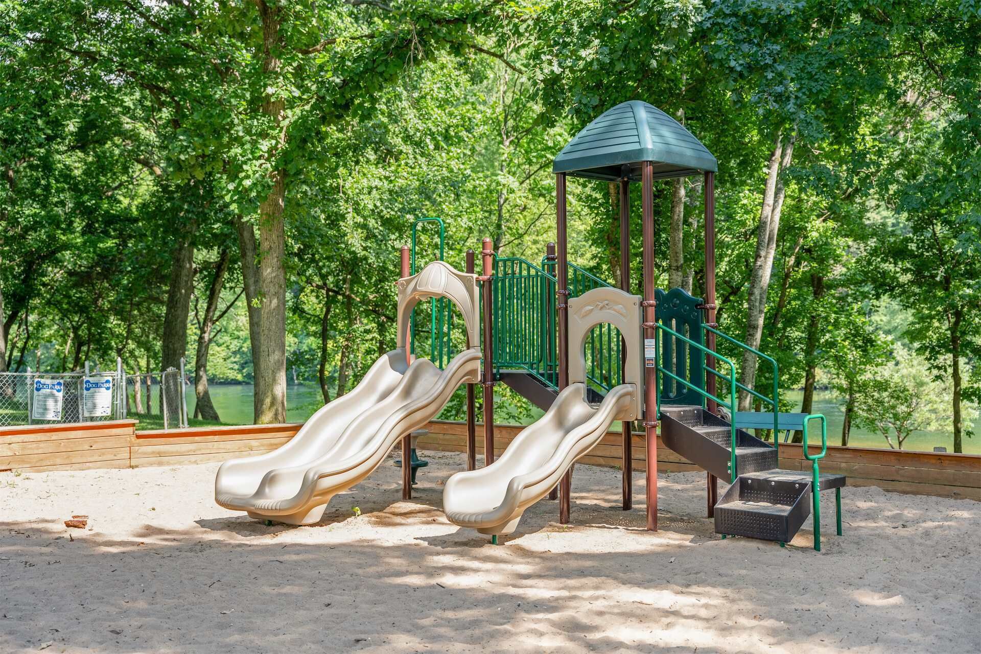 A playground with two slides, a climbing structure, and a small shelter.
