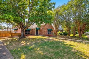 A two-story brick house with a front yard, a wooden fence, and a large tree. - Dalraida 3BR Near Gunter Annex & Downtown (Montgomery)