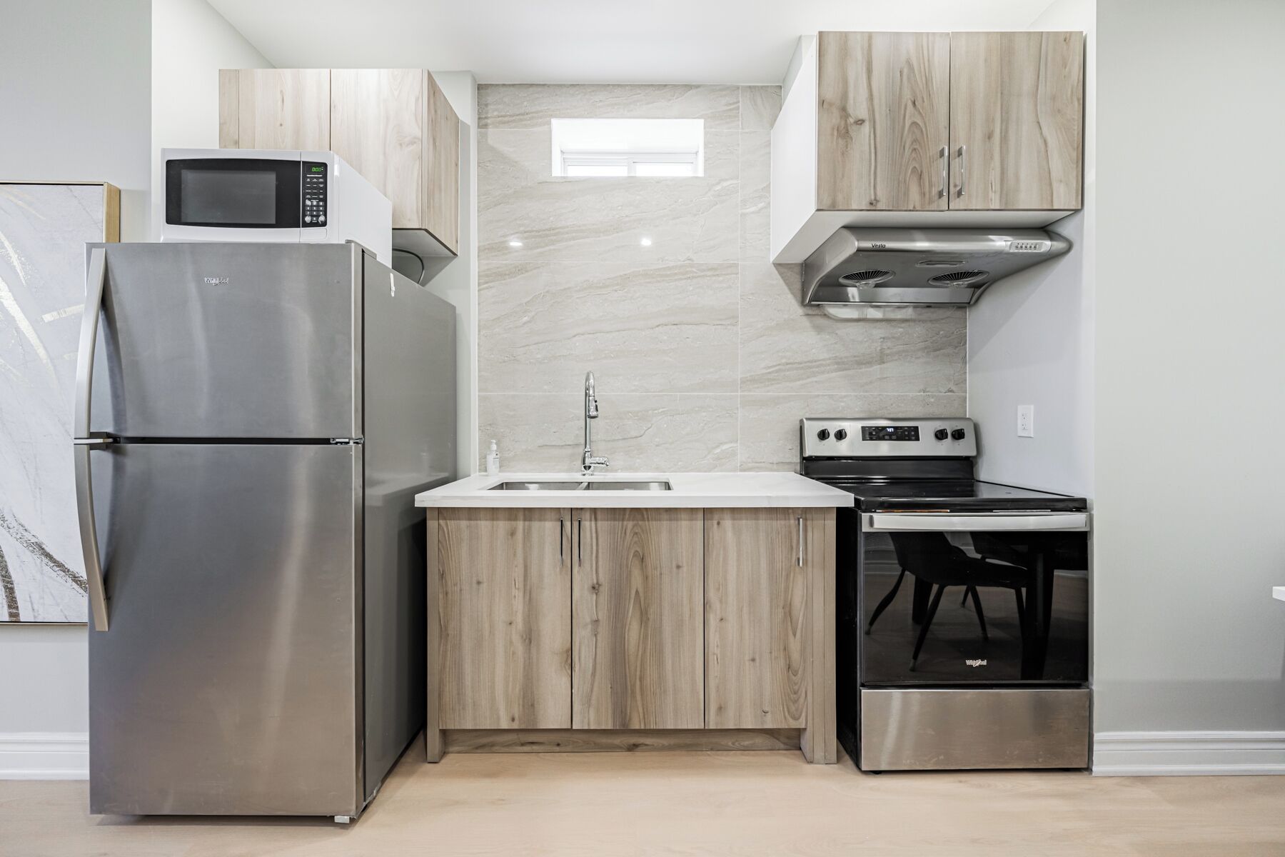 A compact kitchen with a refrigerator, microwave, sink, stove, and oven.
