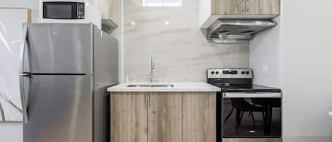 Cocina compacta con refrigerador, microondas, pileta, estufa y horno.