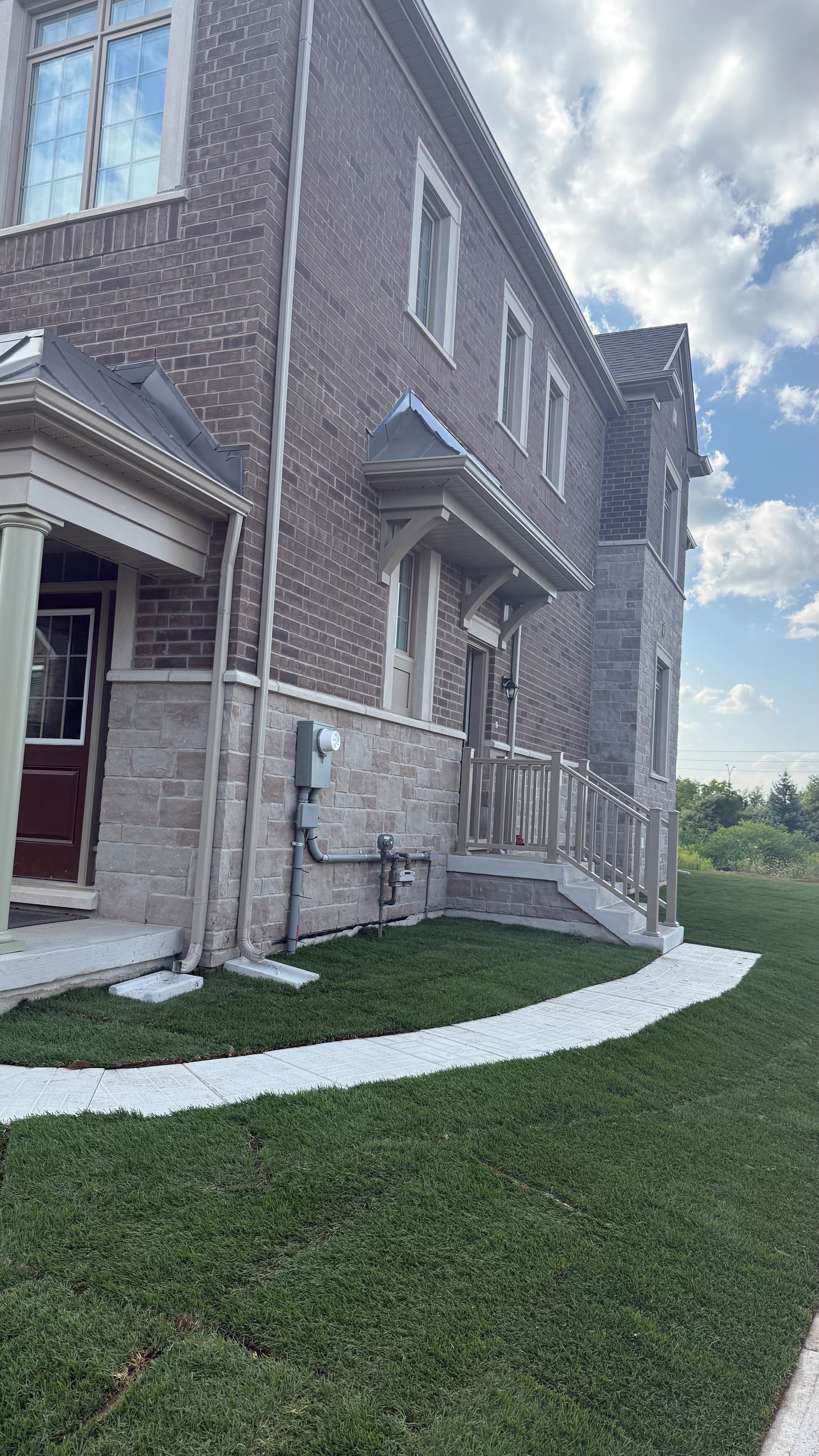 A two-story building with a brick facade, a covered porch, and a well-maintained lawn.