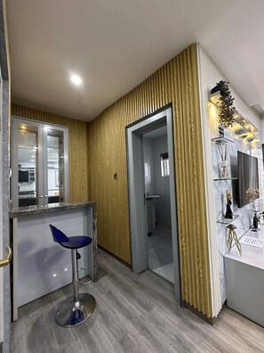Eine moderne Küche mit Barbereich, einem blauen Barhocker und einer Wand mit Holzverkleidung.