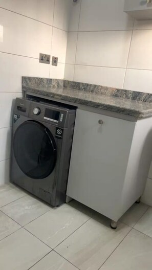 A compact laundry area with a washing machine and a small cabinet. - Premium 1-Bedroom Apartment in Lekki 1 with Fast Wi-Fi & 24/7 Power (Lekki)