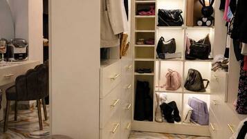 Um closet amplo com várias prateleiras, gavetas e espaço para pendurar roupas, contendo diversas bolsas e sapatos.
