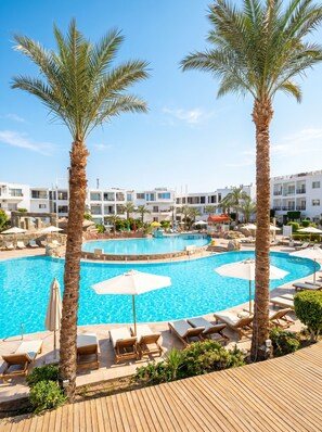A resort pool area with palm trees, lounge chairs, and a clear blue sky. - Gold Suite at Naamabay—accommodates up to 4 people with free beach transfer (Sharm el-Sheikh)