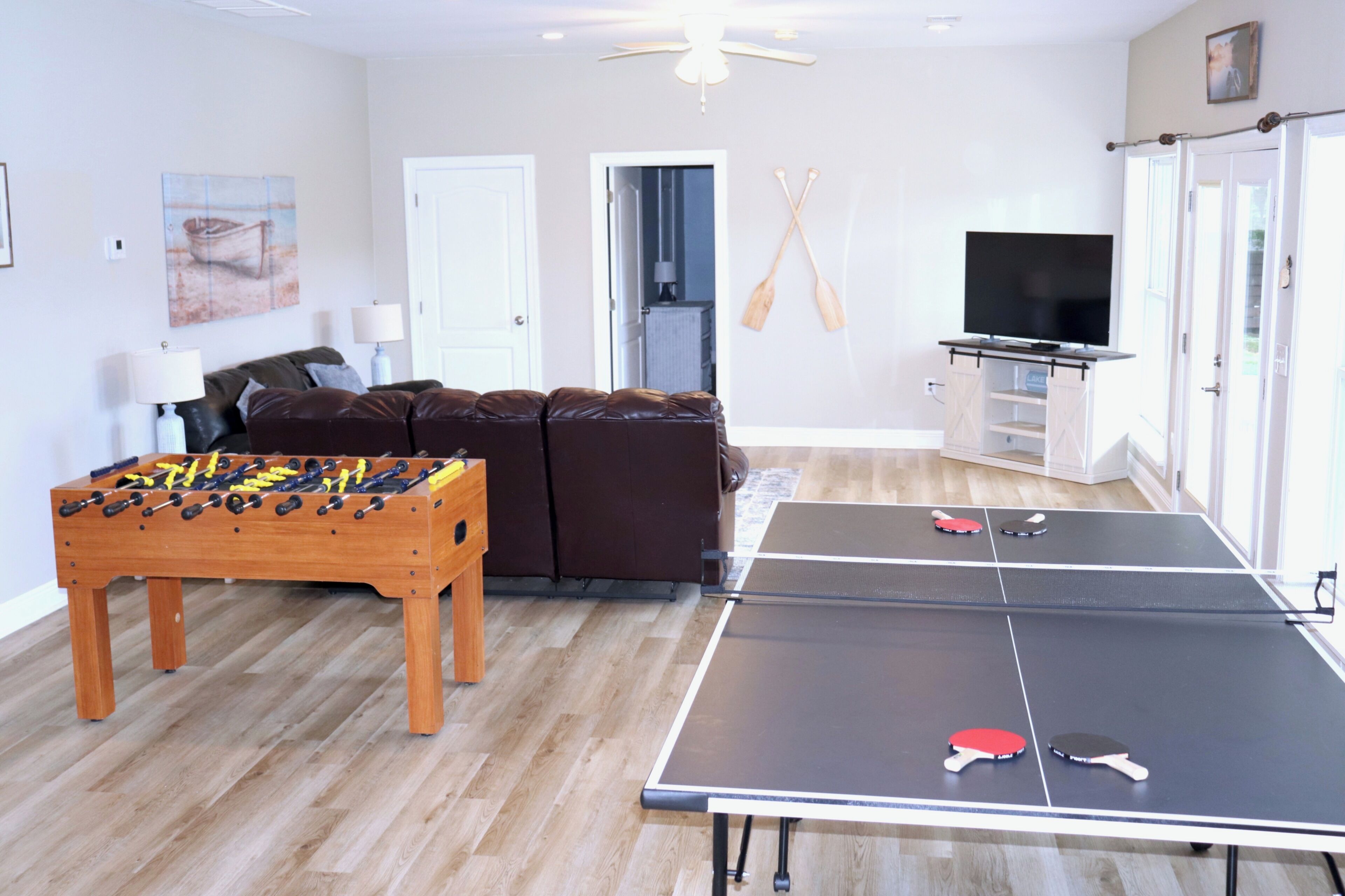 Una sala de estar con mesa de fútbol de mesa, mesa de ping pong y televisor.