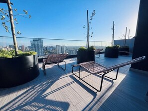 A rooftop terrace with two lounge chairs, potted plants, and a city view. - Apartment, 2BR/2BA, AC and Heating, parking y GYM. (Ñuñoa)