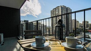 En balkon med et bord dækket til to personer, to kopper, et glas og en lanterne.