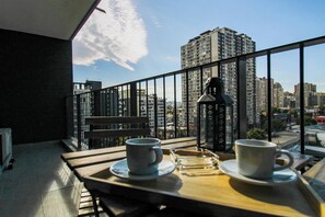Ein Balkon mit einem Tisch für zwei Personen, zwei Tassen, einem Glas und einer Laterne.