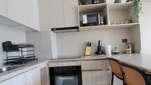 Et moderne køkken med indbygget ovn, mikroovn og kaffemaskine.