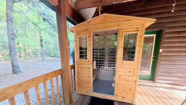 A wooden cabin with a porch, a door, and a window.