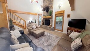 A living room with a fireplace, a television, and a staircase. - Secluded A-Frame Cabin w/ Sauna+Pool Table+ Fire Pit on Petit Jean Mountain (Morrilton)