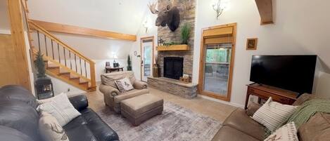 Ein Wohnzimmer mit Kamin, Fernseher und einer Treppe.