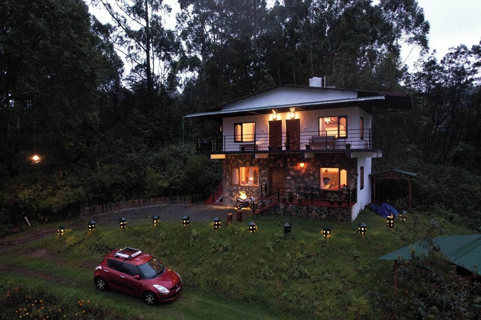 A two-story house with a stone facade, a balcony, and a car parked in the driveway.
