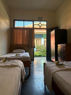A hotel room with two beds, a wooden headboard, a wardrobe, and a view of the outside. - La Casa del Paucar (Iquitos)