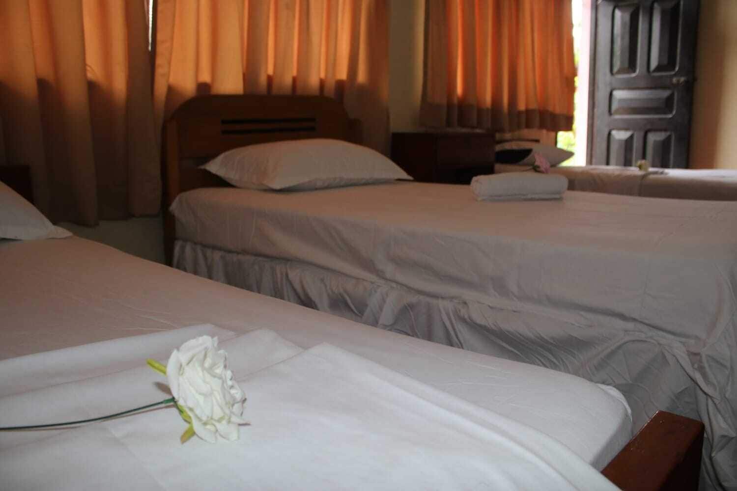 A hotel room with two beds, a wooden headboard, and a nightstand with a lamp.