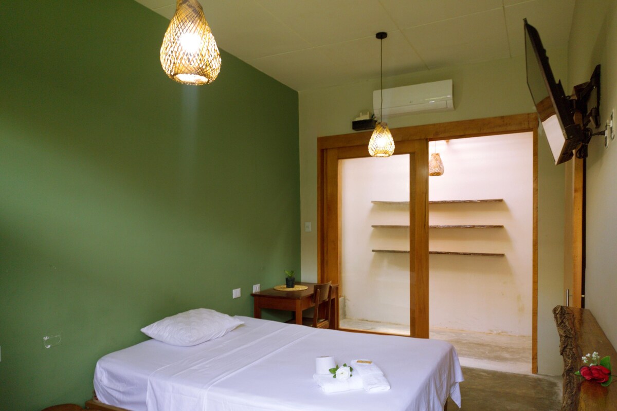 Una habitación con una cama, una mesita, una silla y una lámpara colgante.